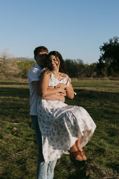 David picking put Elizabeth from behind and twirling her at their couples session in Murrieta, California.