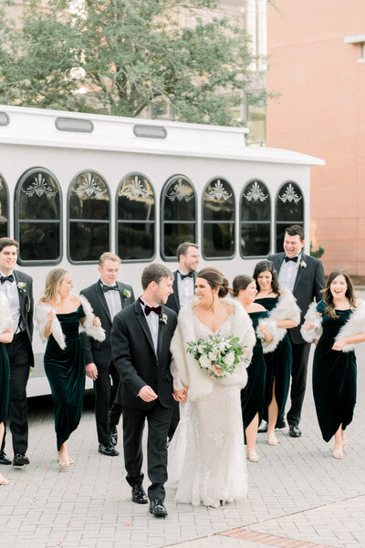 Couple walking with bridal party in front of charleston trolley at cedar room wedding day