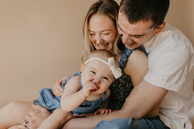 mom, dad and new baby girl smiling while embracing