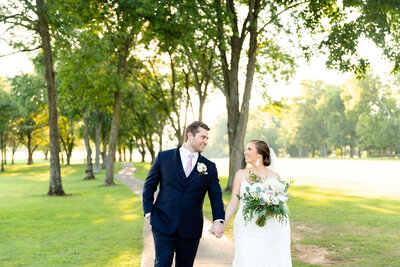 Bride and groom walking along a tree-lined path