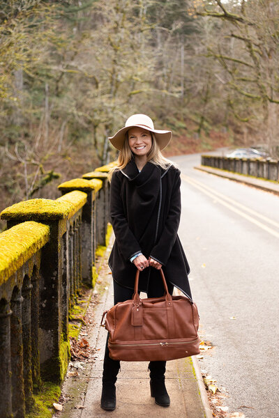 portland branding photoshoot with woman standing on bridge in the Gorge with leather handbag. 