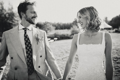 bride and groom looking at each other lovingly on their wedding day while holding hands in black and white.