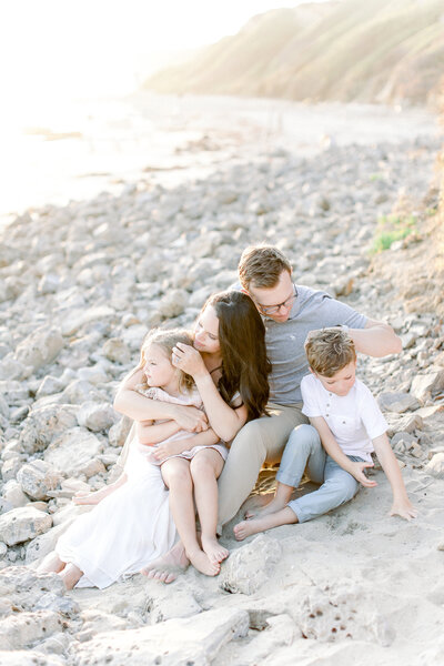 Photographer, Kristin Wood, sits on a Sherwood Island beach with her husband and two children