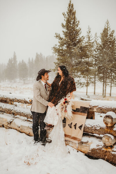 bride and groom sitting on rustic wood fence during their elopement