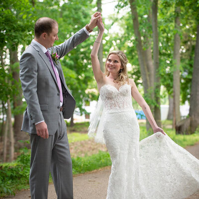 groom twirls bride on treelined street