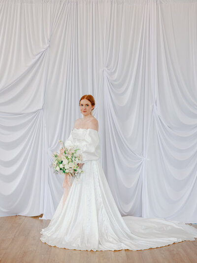 Bridal portrait with white draping and elegant white flowers.