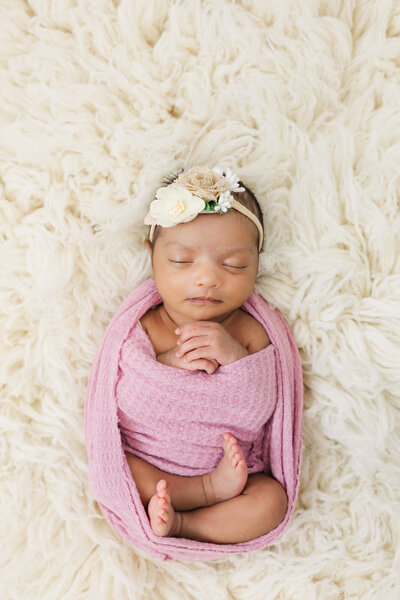 Baby girl sleeps in purple swaddle during lifestyle newborn session in Dekalb, Georgia