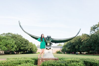 College senior stands by statue on campus
