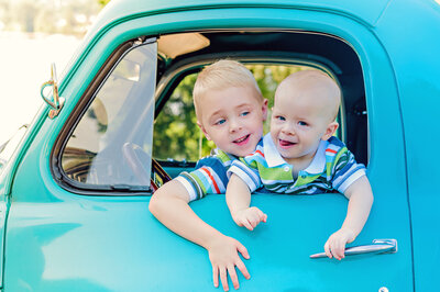 Two little brothers in a vintage blue truck window