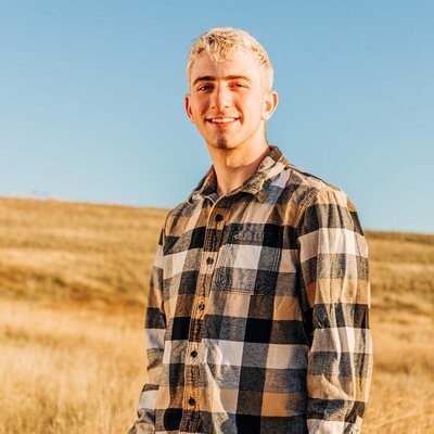 Senior photo of young man standing in a golden field on a sunny day in Missoula, MT