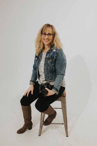 photographer sitting on a stool with camera while smiling