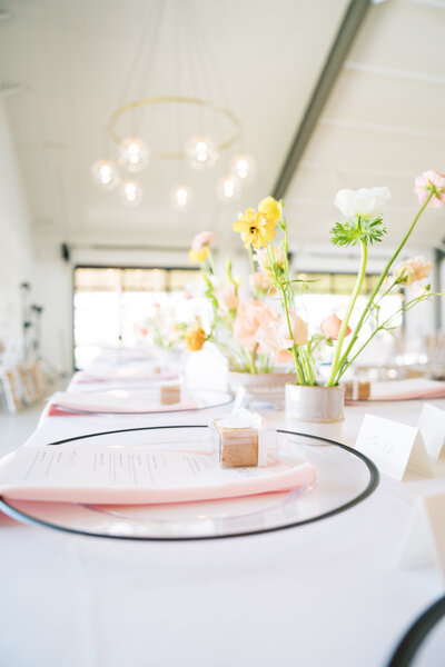 Bright wedding tablescape with pink napkins and yellow florals