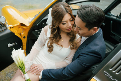 Bride and groom posing in a vibrant yellow Porsche during their stylish Vancouver wedding, captured by Vintage Gem Photography.
