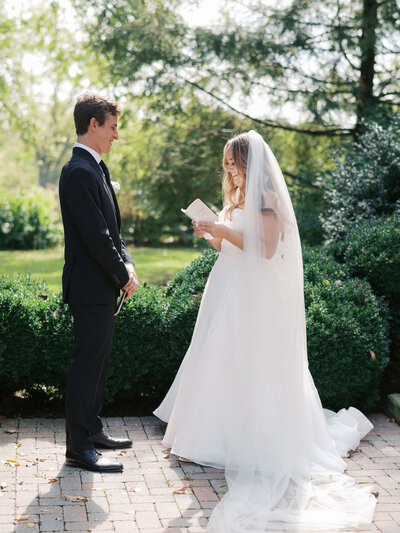 A photo of a gorgeous couple stands in the sunlight while they read their private wedding vows to each other before their wedding  ceremony in the DMV area