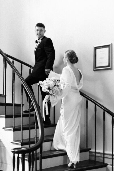 black and white photo of bride and groom walking up the stairs