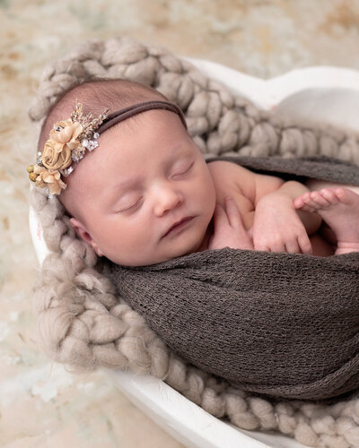 Adorable wrapped newborn with flower headdress