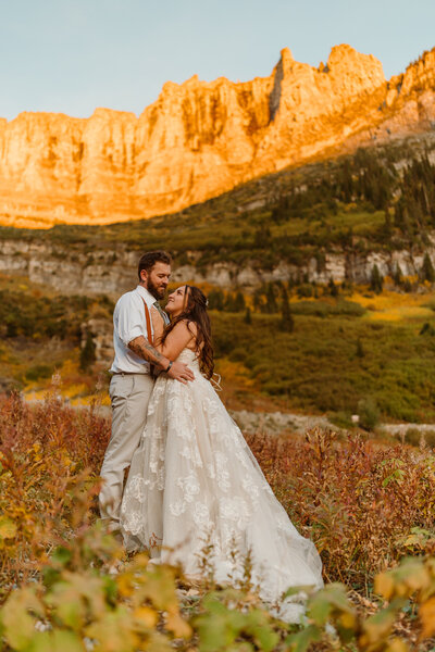 bride and groom posing by mountains