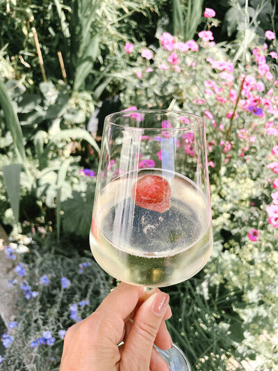Glas witte wijn in de tuin met bloemen