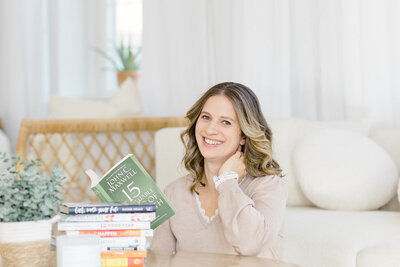 Woman smiling at camera, reading personal growth books