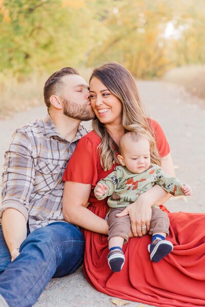 husband kisses wife's cheek with baby on her lap, Boulder Colorado