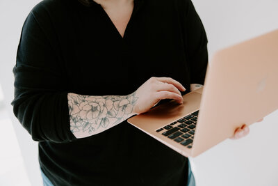 Female entrepreneur with floral tattoo checking business messages on her smartphone, smiling and focused during remote workday