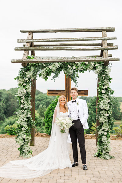 a newlywed couple posing by a wooden cross