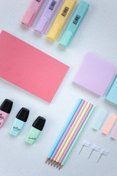 Colorful highlighters on counter next to pink and purple post it notes