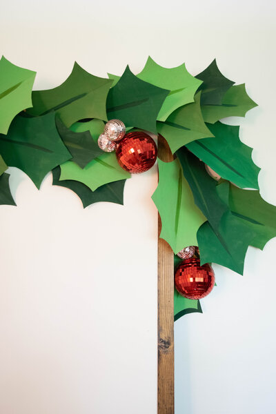 A paper holly garland with disco balls as berries