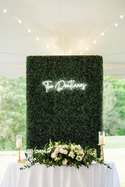 a green hedge wall with a last name on it for wedding