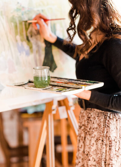 Behind the scenes image of an artist adding details to a watercolor portrait of a wedding