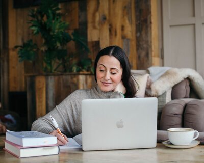 Mariella seated behind a laptop smiling