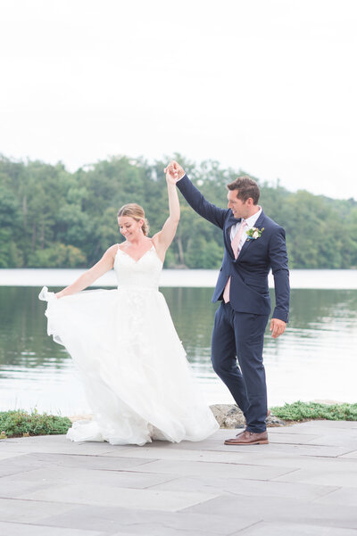 bride and groom twirl at the waters edge at north shore house