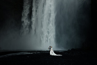 bride and groom walking infront of waterfall