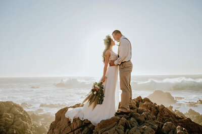 couple standing on beach rocks