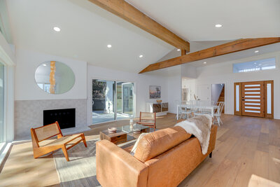 Bright and spacious open-concept living room with vaulted ceilings, wood beams, and modern finishes, showcasing a home listed for sale by AW Development