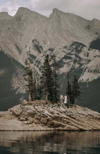 couple holding hands in a picturesque  mountain location of Banff national park on their wedding day