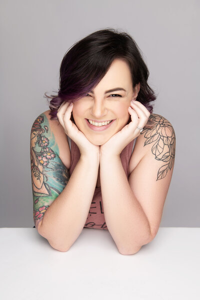 olivia belle marie boudoir owner headshot laughing head in hands with tattoos
