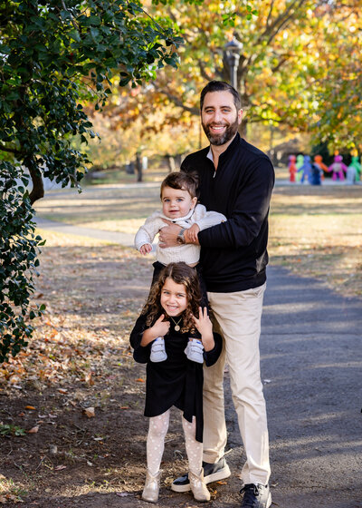 Goofy photo of father posing with kids at an Essex County, New Jersey park in the fall.