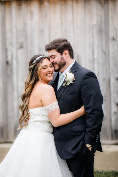 Portrait of bride and groom smiling and hugging at Barn at Murphey Farm wedding.