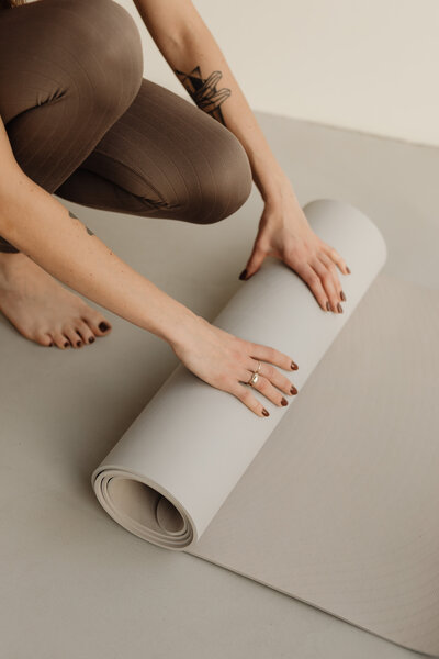 Junge Frau rollt Yogamatte aus.