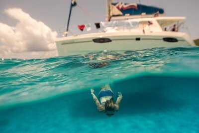 jill diving under a boat in blue water
