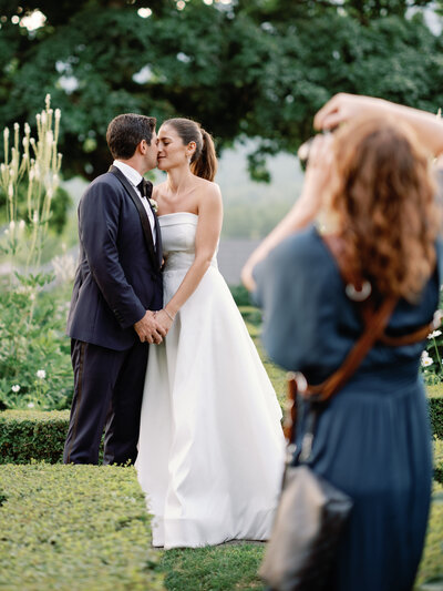 Photographer documenting romantic moment with bride in kelly faetani gown at black tie wedding hildene vermont