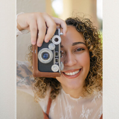 Photo of Wedding photographer Sarasota holding a film camera and smiling. 