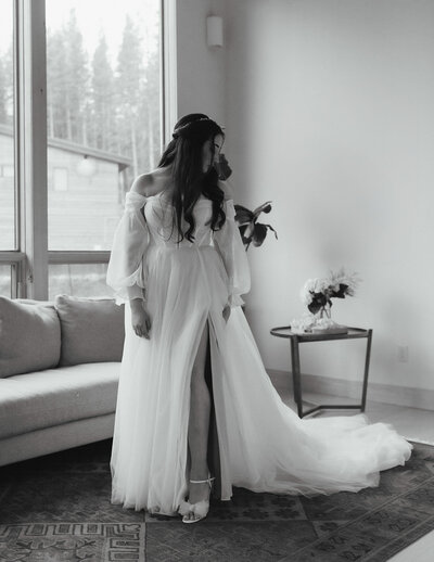 Black and white photo of bride wearing and admiring her elegant wedding gown