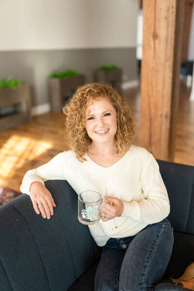 Woman sitting on a couch holding a glass mug