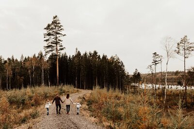 Familj går på väg i skogen hand i hand.
