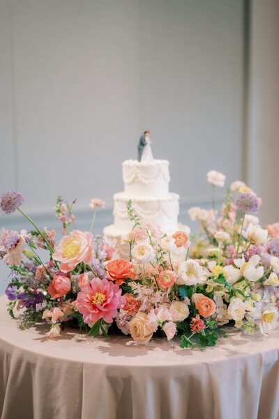 Outdoor table setting with pastel flowers, pink balloons backdrop.