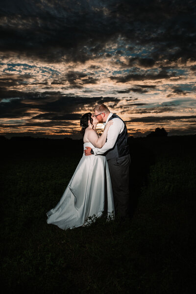 A bride and groom snuggle and smile while standing in a garden trail with a Milwaukee Wedding Photographer