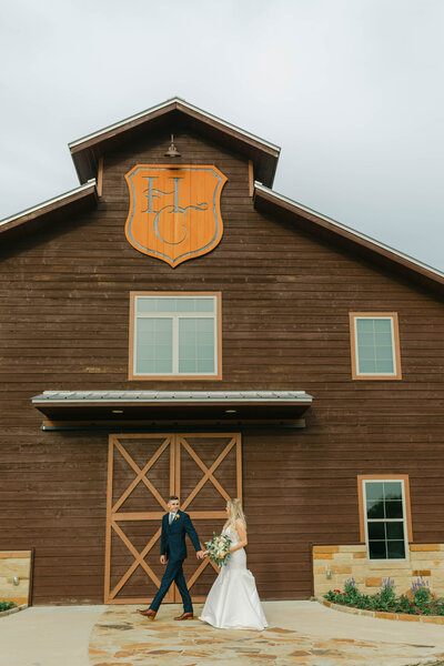 bride and groom walking in front of barn at hidden creek venue