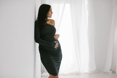 pregnancy shoot with Laurie Baker, woman leaning against wall holding belly
